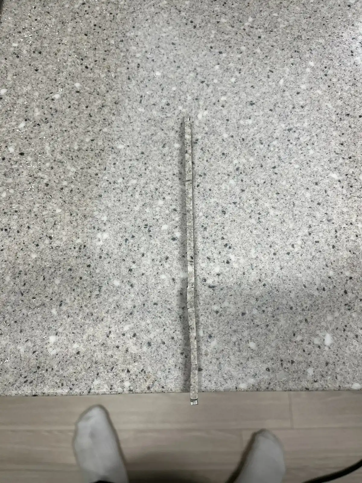 균열선이 지나던 자리에 같은 계열의 가는 보강 조각을 한 줄로 이어 놓은 싱크대 상판, 보수 진행 중 모습