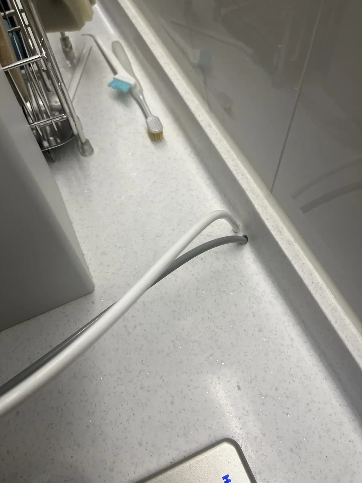 흰색 호스와 회색 전원선이 상판 뒤쪽 턱 아래의 구멍으로 들어가는 정수기 배관 통과 부위, 복원 이전