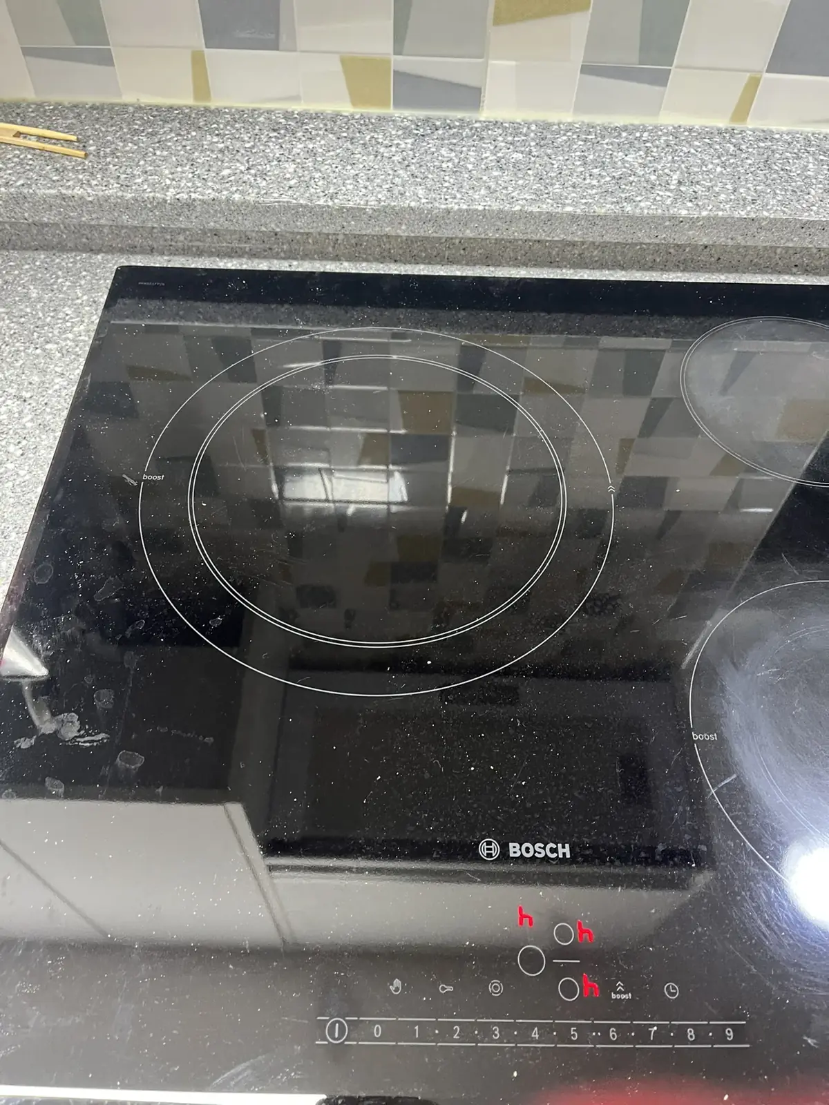 작업 후 매립된 인덕션 쿡탑 윗면의 화구 표시와 아래쪽 터치 조작부, 뒤쪽 상판 단턱과 타일이 보이는 근접 모습