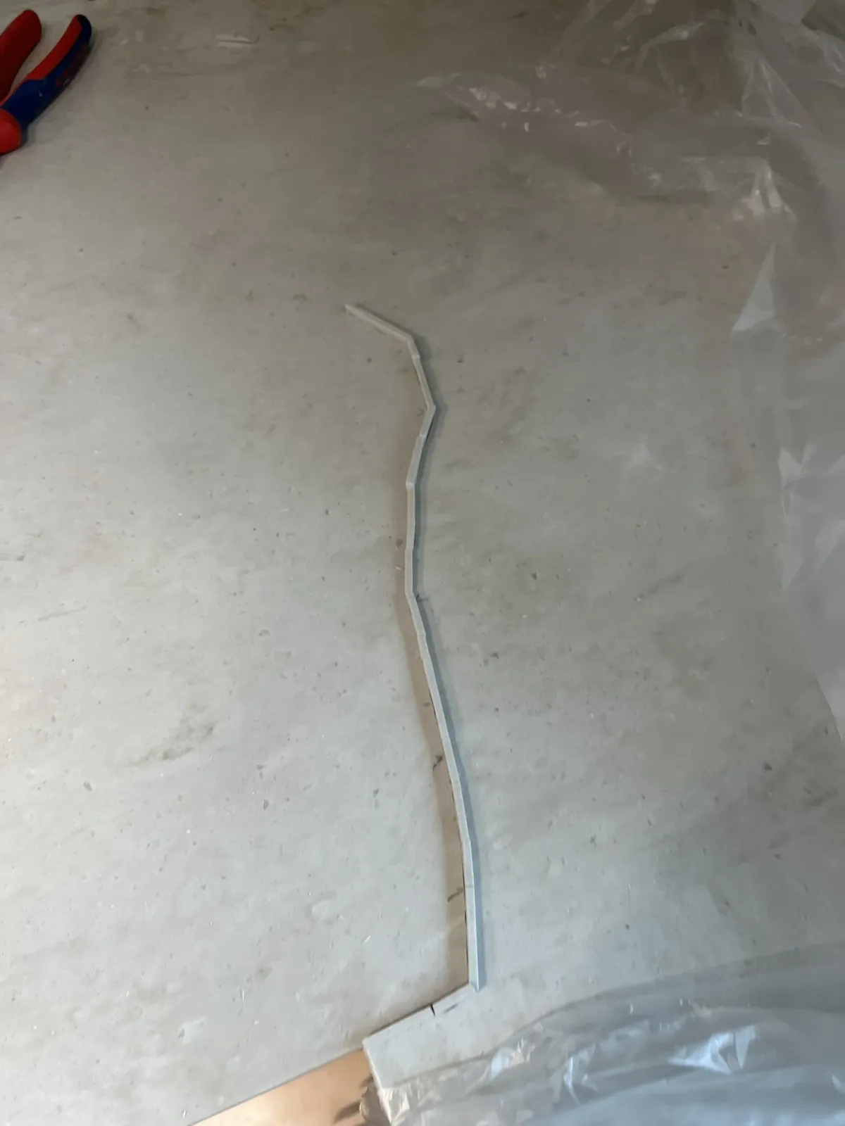 크림색 인조대리석 싱크대 상판 위에 곡선으로 늘어놓은 가는 매립 조각과 작업용 비닐이 보이는 보수 진행 중 모습