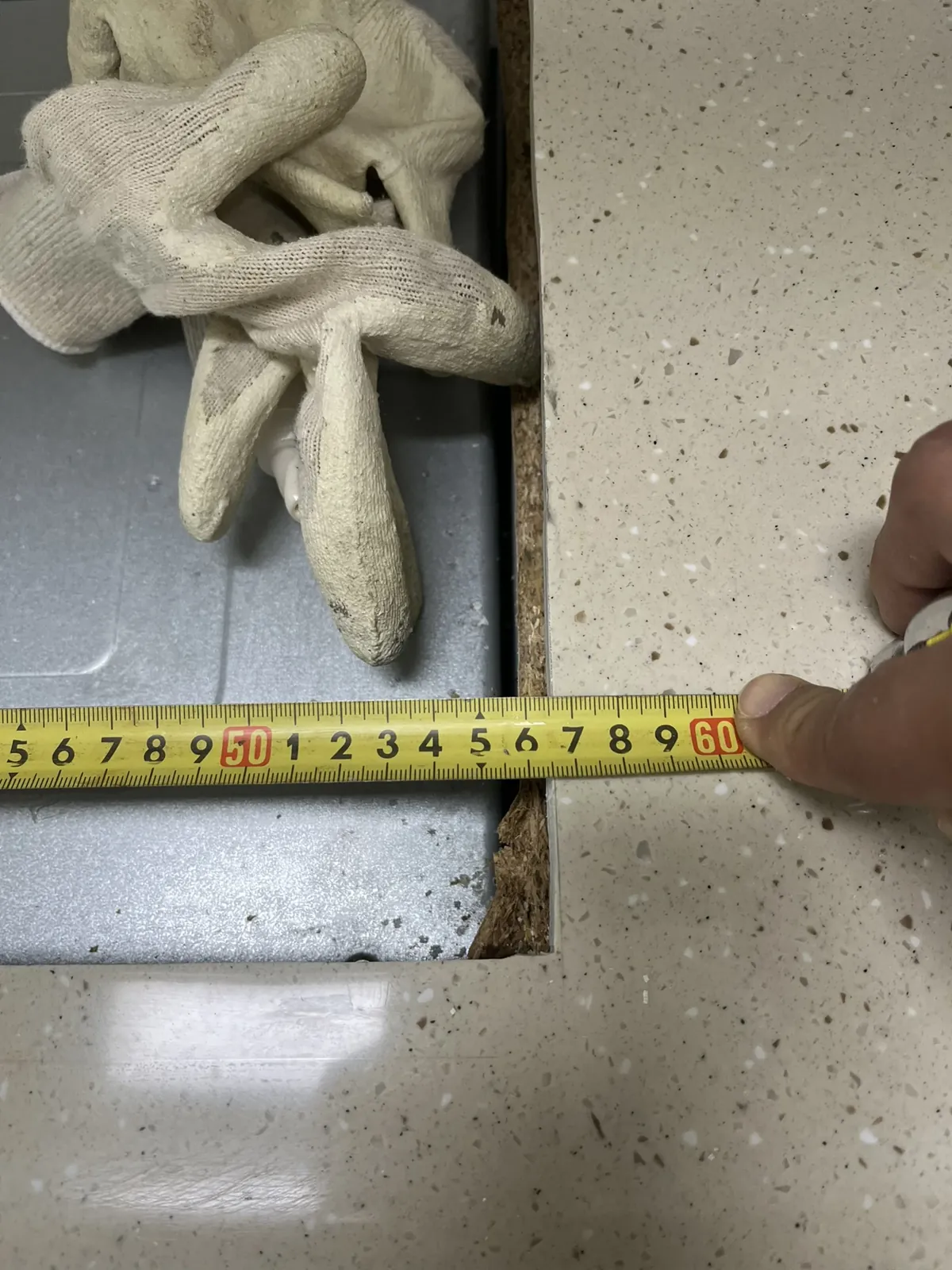 작업 전 인조대리석 상판 개구부 폭을 줄자로 재는 모습과 노출된 갈색 받침 보드 단면